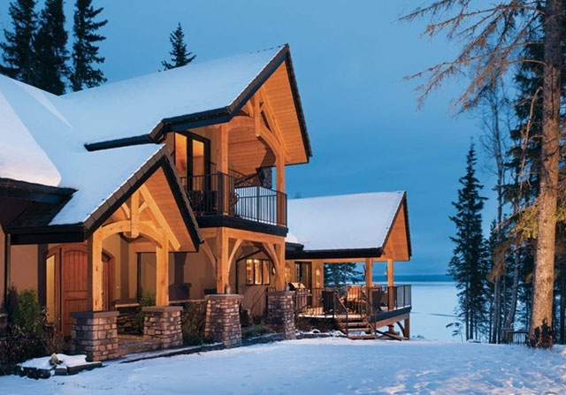 timber frame home in the winter with snow covering the ground and rooftop at dusk