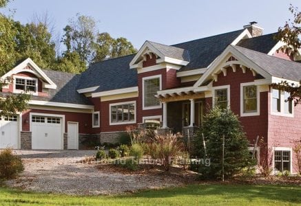 red timber frame home with exposed exterior framing and a three car garage