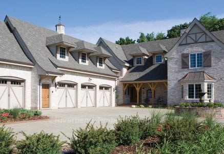 timber frame home with grey stone exterior and a four car garage