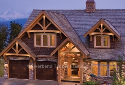 timber frame home at deck with the lights on and a mountain in the background