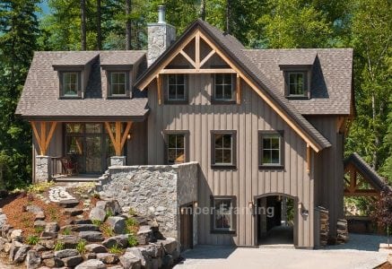 grey timber frame home with sunlight shining down and a forest background