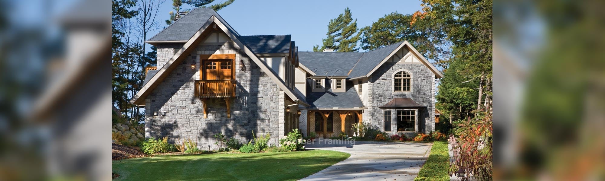 timber frame home with a grey stone exterior and a personal balcony