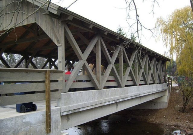 timber frame bridge with grey exterior timber frame and concrete foundation