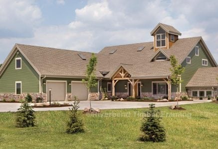 green exterior timber frame home with a two car garage