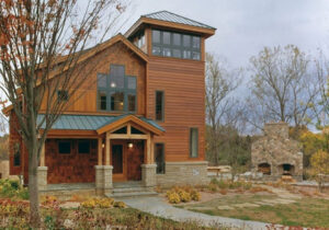 timber frame home with stone pillars and natural wood finish with a green metal roof